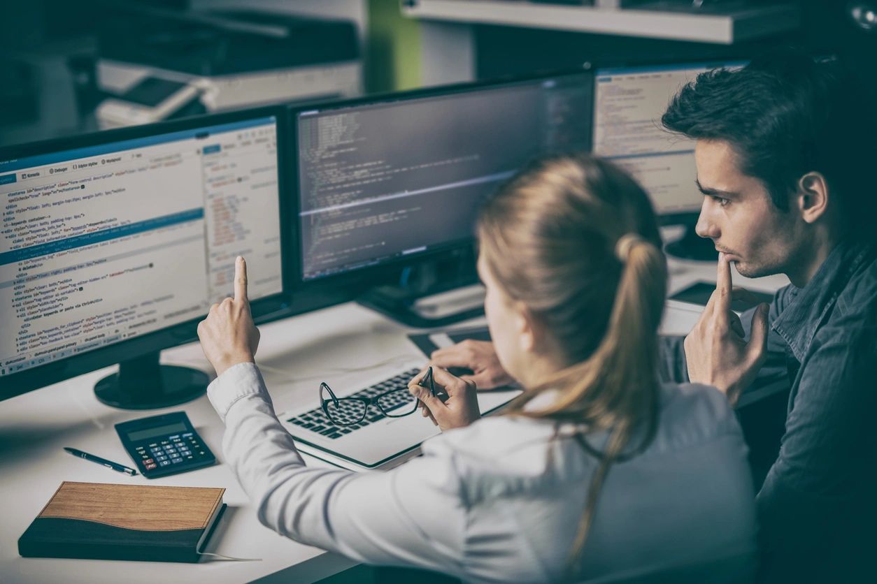 Two people looking at software for quality assurance testing.